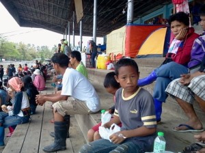 A boy nibbles on a snack as his elders wait for food rations at the New Bataan elementary grandstand.