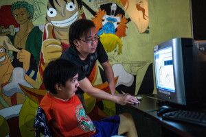 Take One President and CEO Eric Tansingco assists an animator with mobility disability. Photo by MARIO IGNACIO IV