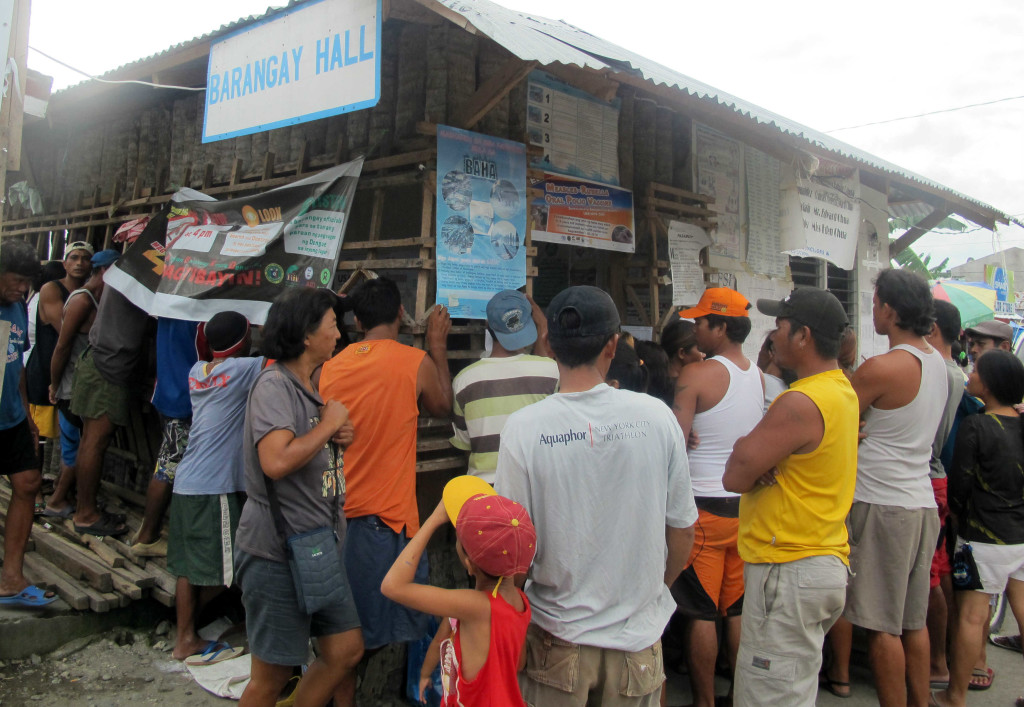 Barangay 88 residents gather at the village hall to find out who gets to move to shelters next. Only 43 of 330 families have moved out of tents.