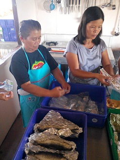Members of the Santa Cruz Women's Association prepare the cooked milkfish for packaging.
