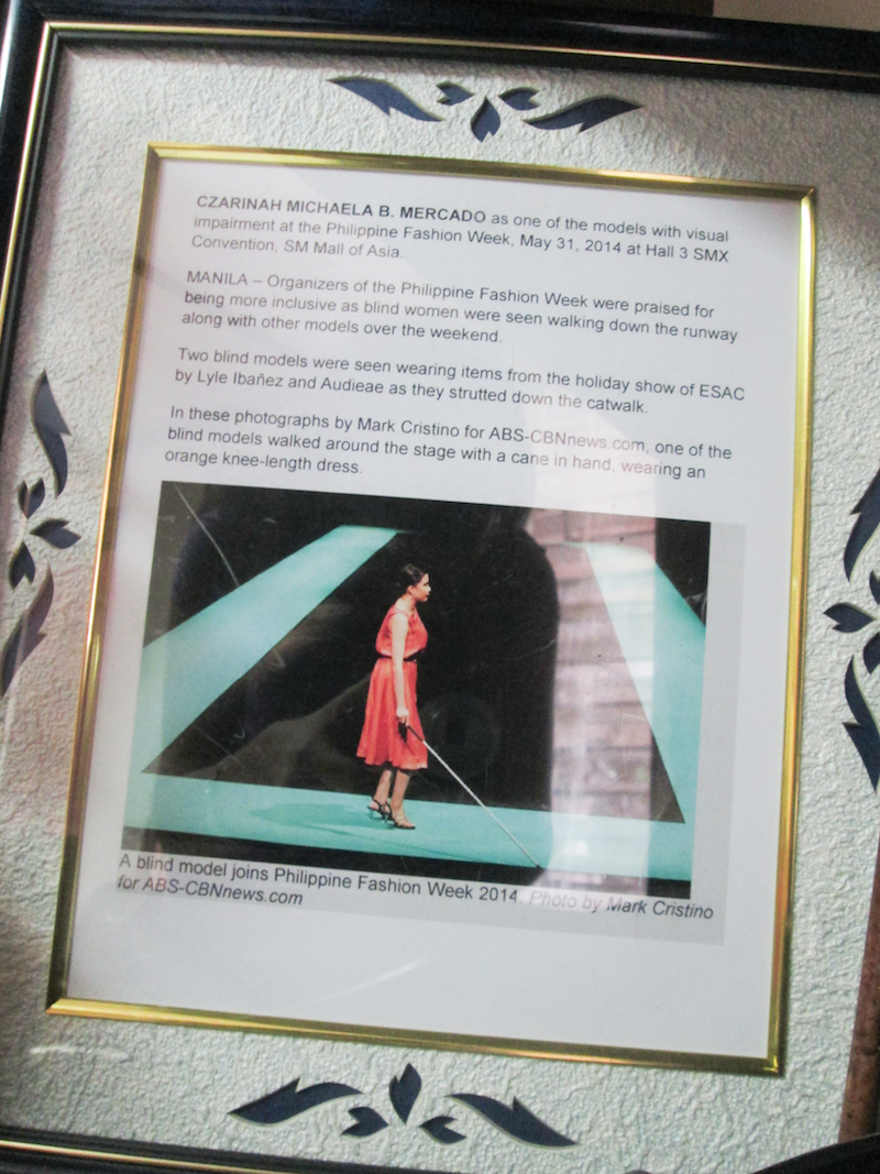 A framed online news article and photo of Mercado's Philippine Fashion Week 2014 appearance is displayed in their home.