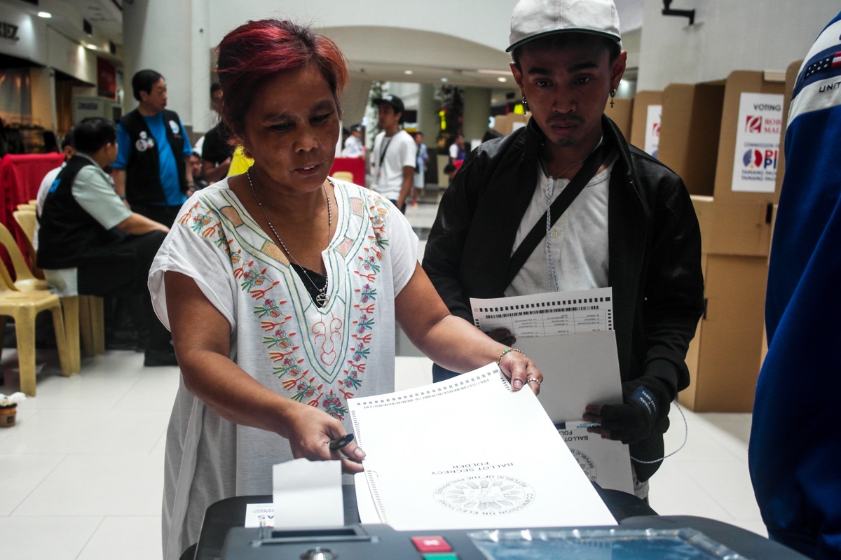 A mock voter feeds her ballot to the vote-counting machine during the mock elections at Robinsons Place Manila on Feb. 13. Photo by MARIA FEONA IMPERIAL