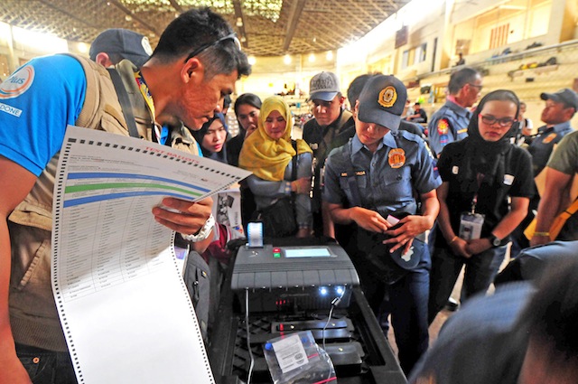 FINAL TESTING. A technician from Smartmatic checks the Vote Counting Machine (VCM) together with policemen and poll watchers at the Lanao del Sur provincial gym in Marawi City, on Sunday, May 8, 2016. Some 200 policemen will take up poll duties to replace teachers who expressed fear of violence during the election on Monday. MindaNews photo by FROILAN GALLARDO