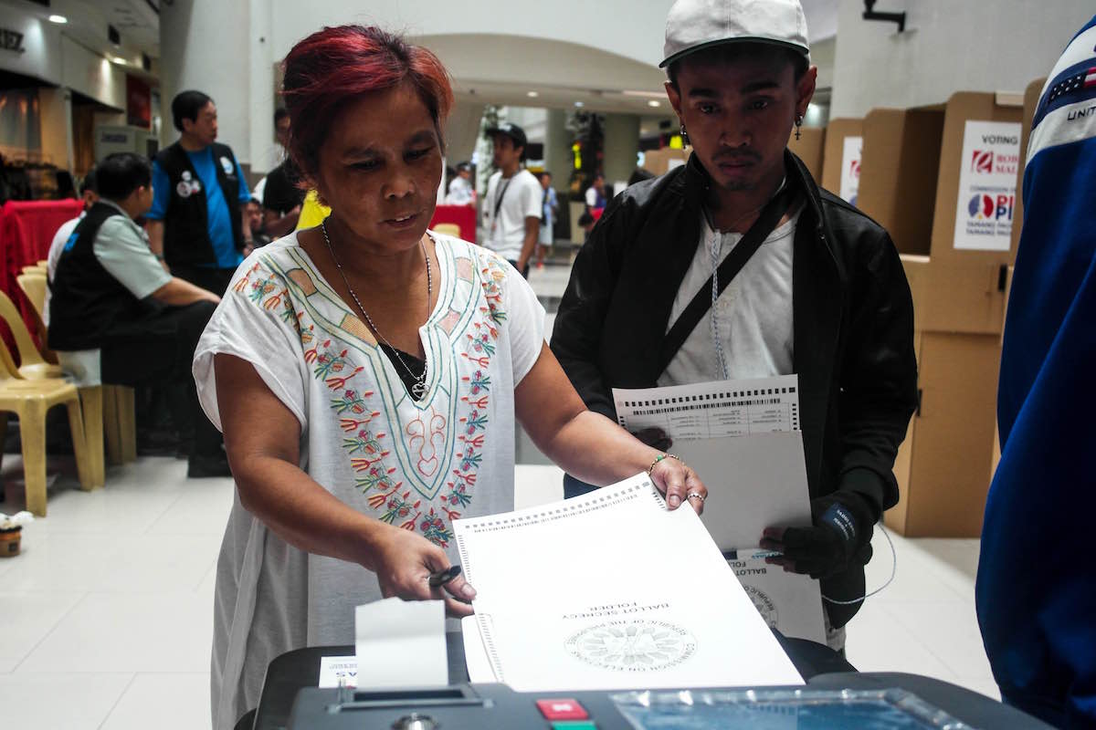 A registered voter feeds her ballot to the vote-counting machine during the mock mall voting at Robinsons Place Manila on Feb. 13. File photo by MARIA FEONA IMPERIAL