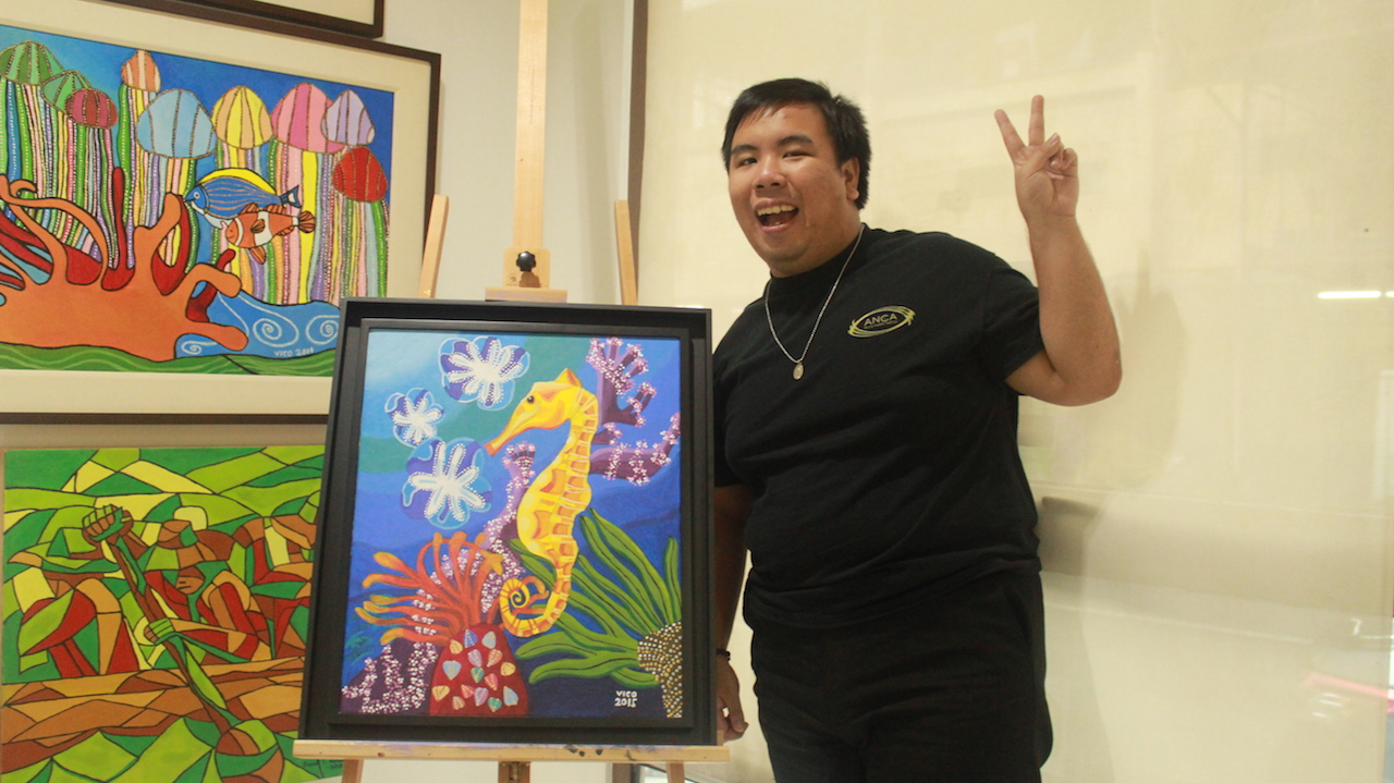 Vico Cham standing next to his painting. Photo by ARIANNE CHRISTIAN TAPAO