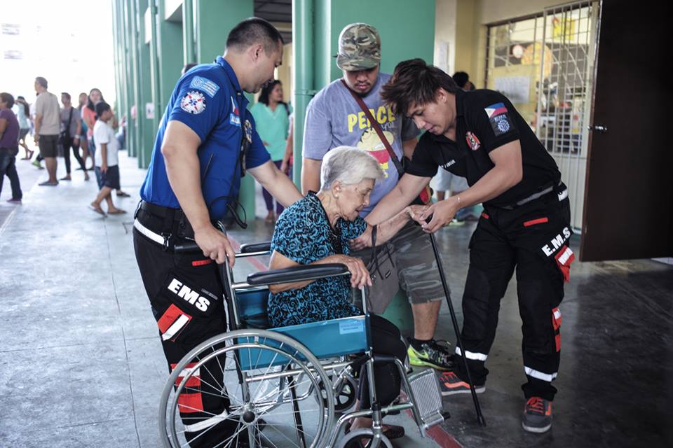 Estellita Sto. Domingo, 8 is assisted assisted by members of the Emergency Care Academy and Rescue Unit to reach her precint on the second floor of Marikina Elementary School. (File photo by MARIO IGNACIO IV)