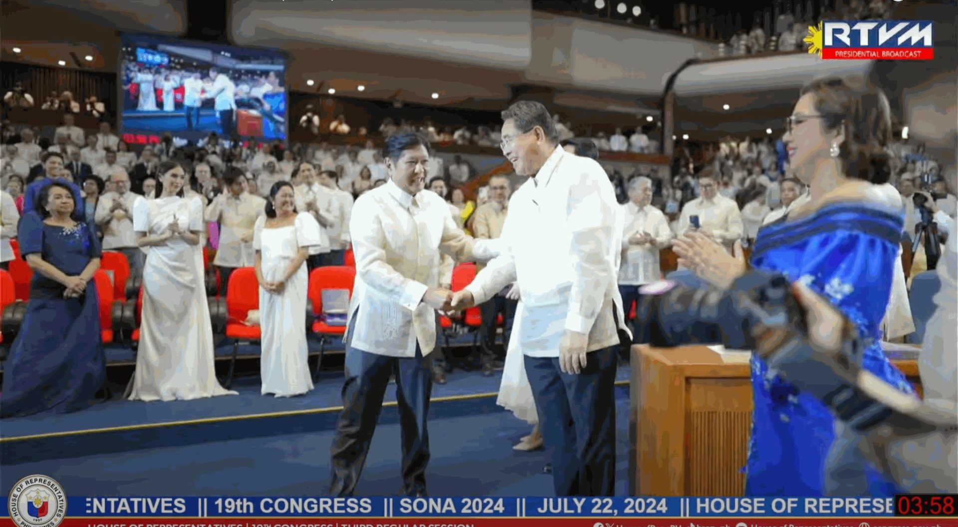 President Bongbong Marcos shakes the hand of Cagayan De Oro Rep. Rufus Rodriguez in front of a crowd of SONA attendees dressed in formal Filipino wear