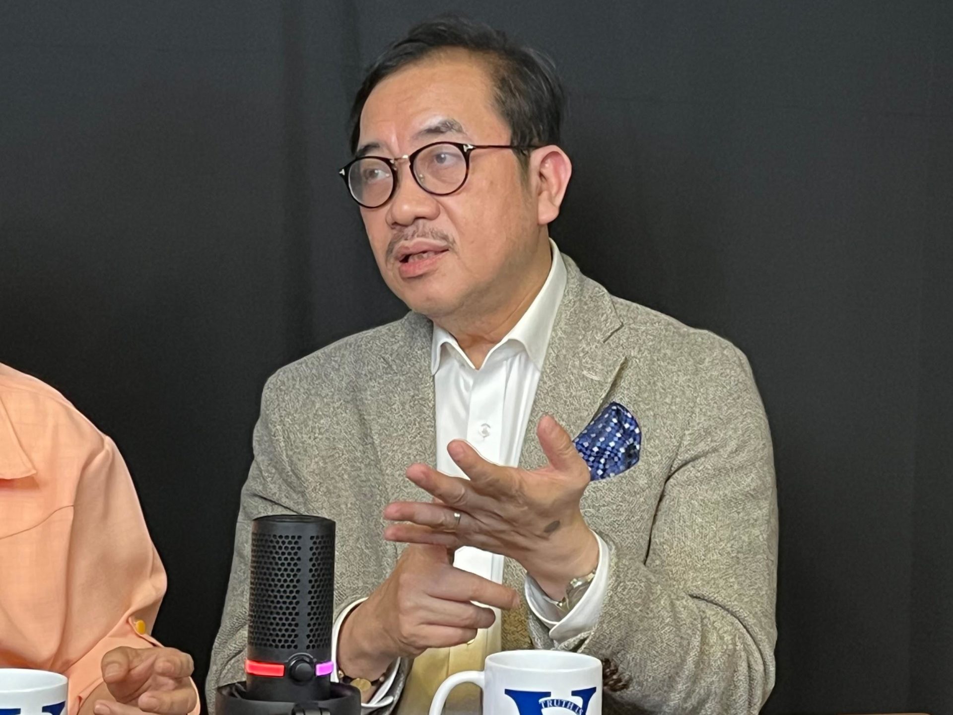 Close-up of Dr. Tony Leachon (in gray) speaking in front of microphone