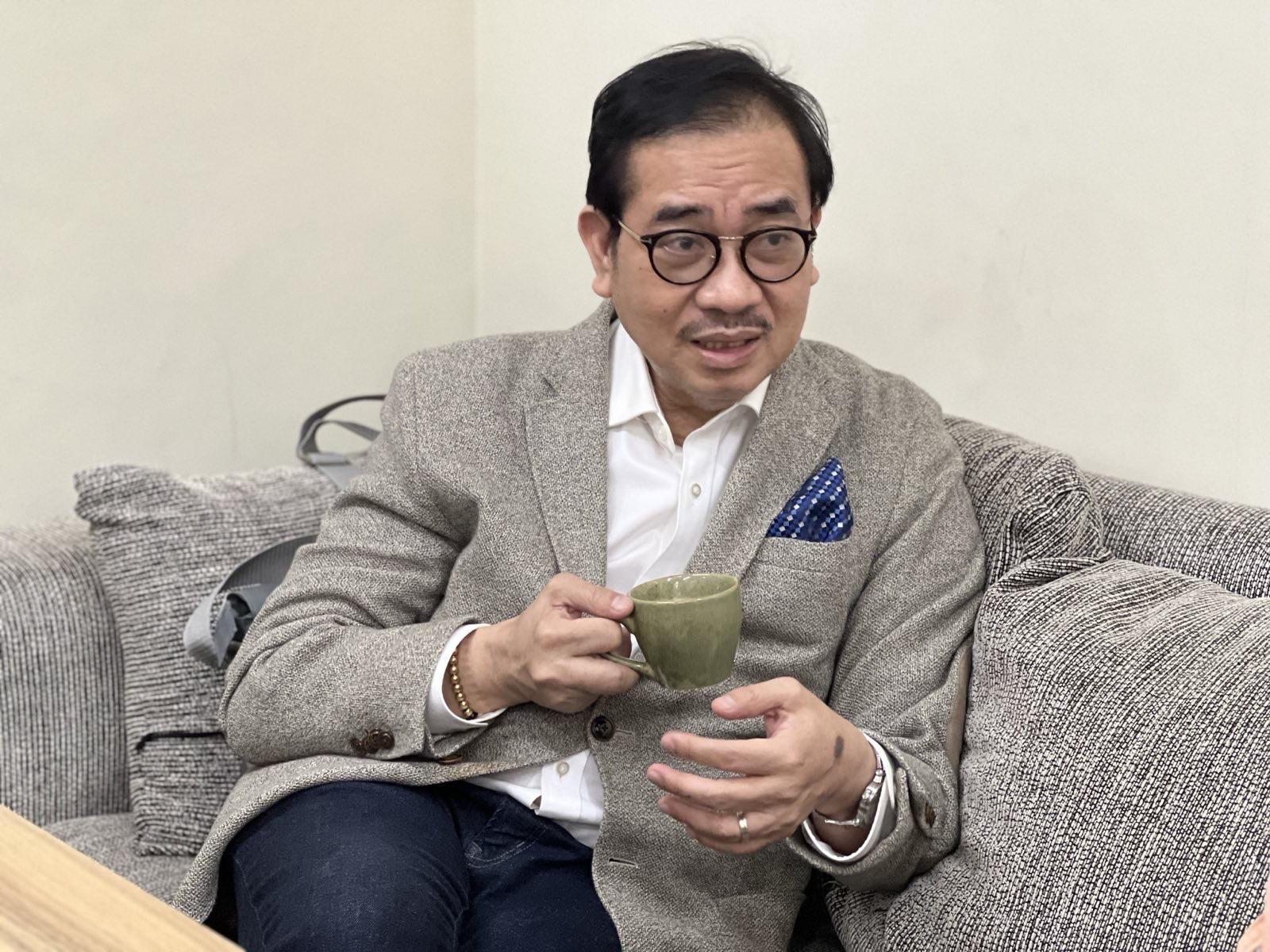 Photo shows Dr. Tony Leachon (in gray) holding a green cup of coffee