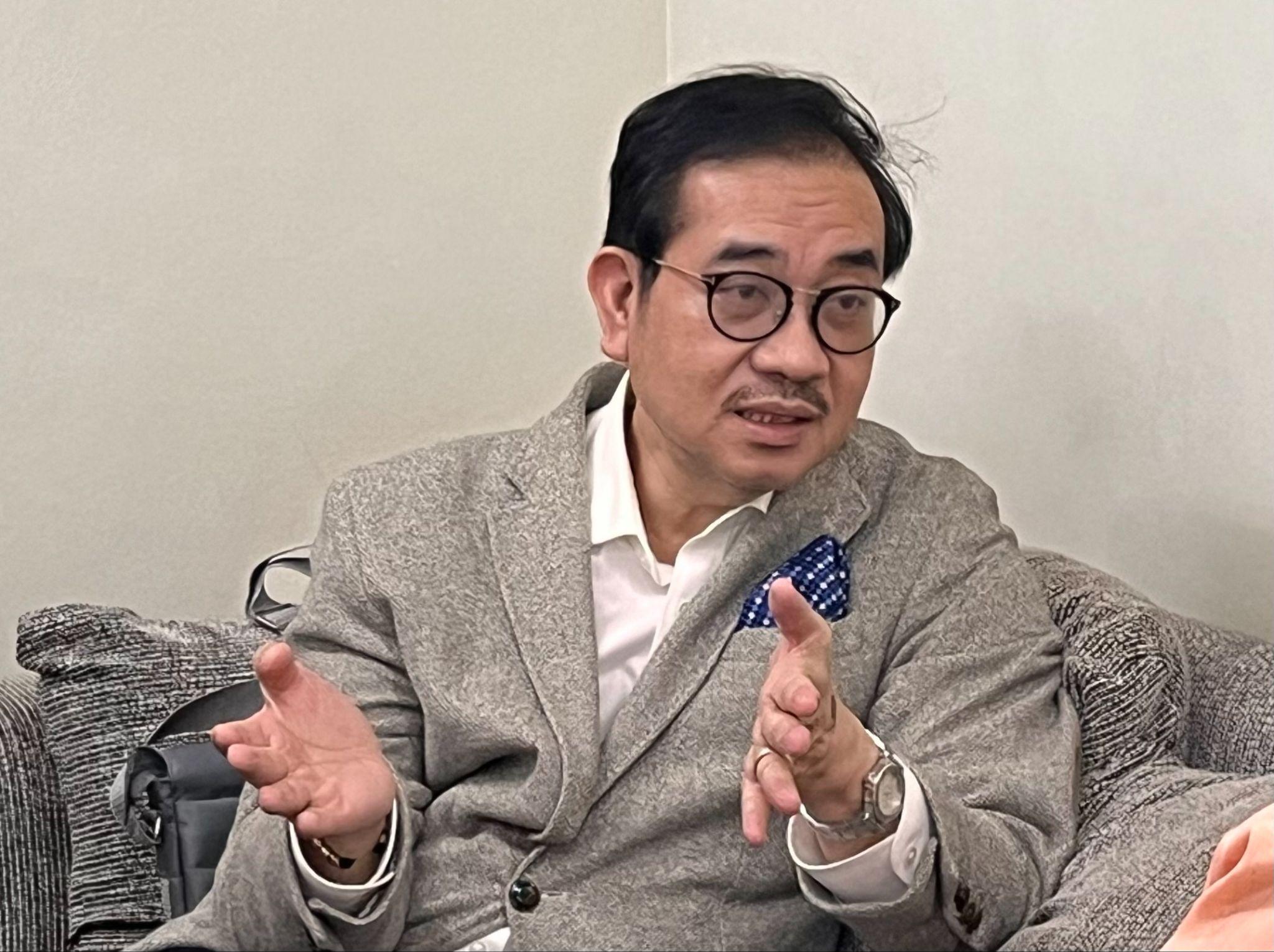 Close-up of Dr. Tony Leachon (in gray) sitting on a couch 