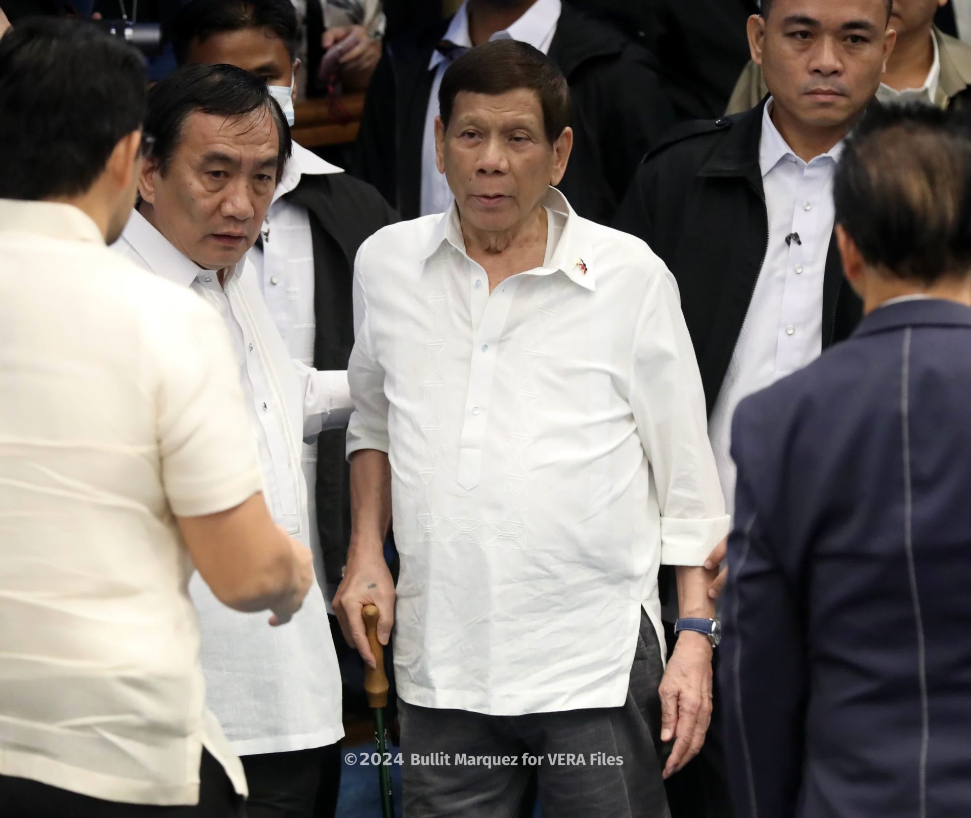 Walking wobbly, former president Rodrigo Duterte, enters the plenary hall of the Philippine Senate currently probing his brutal war on drugs. Photo by Bullit Marquez for VERA Files
