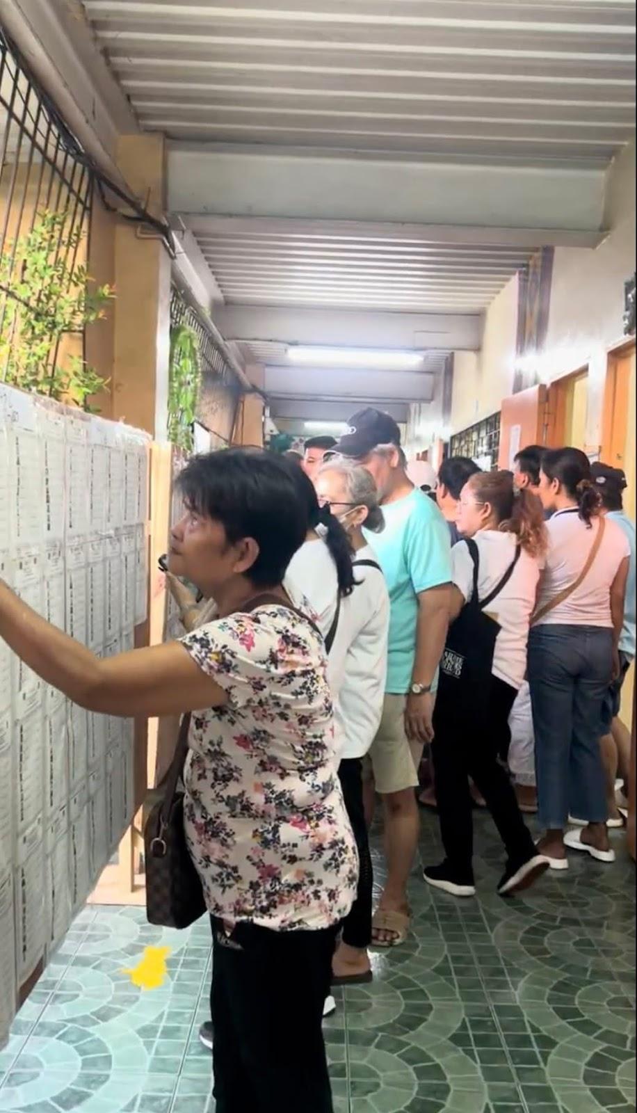 Voters crowd in the school hallway, to look up their classroom assignments at the precinct
