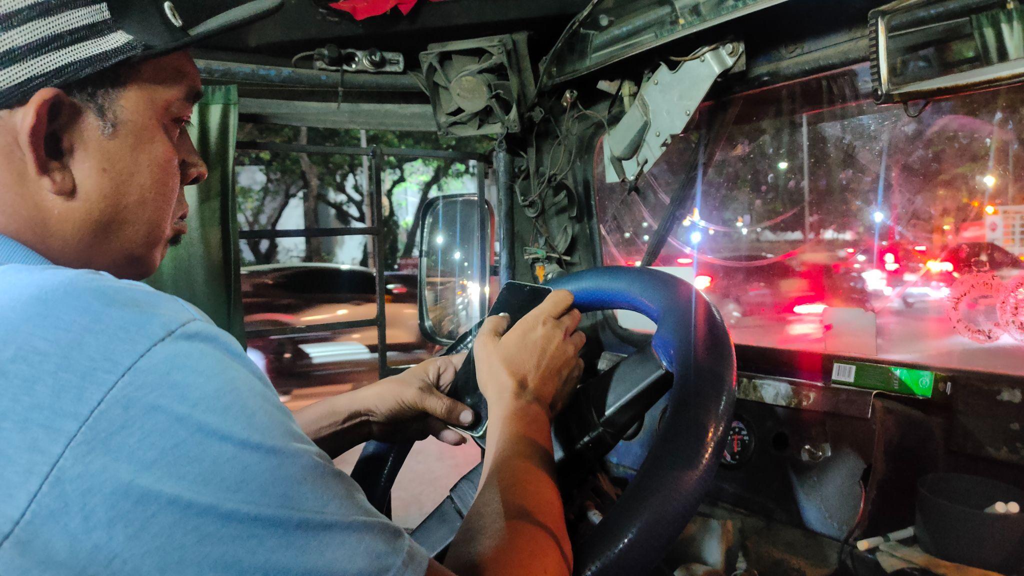 John Aries Jeffrey Tuazon checks his phone while waiting for his jeepney to fill with passengers at the PhilCoA loading area in Quezon City.