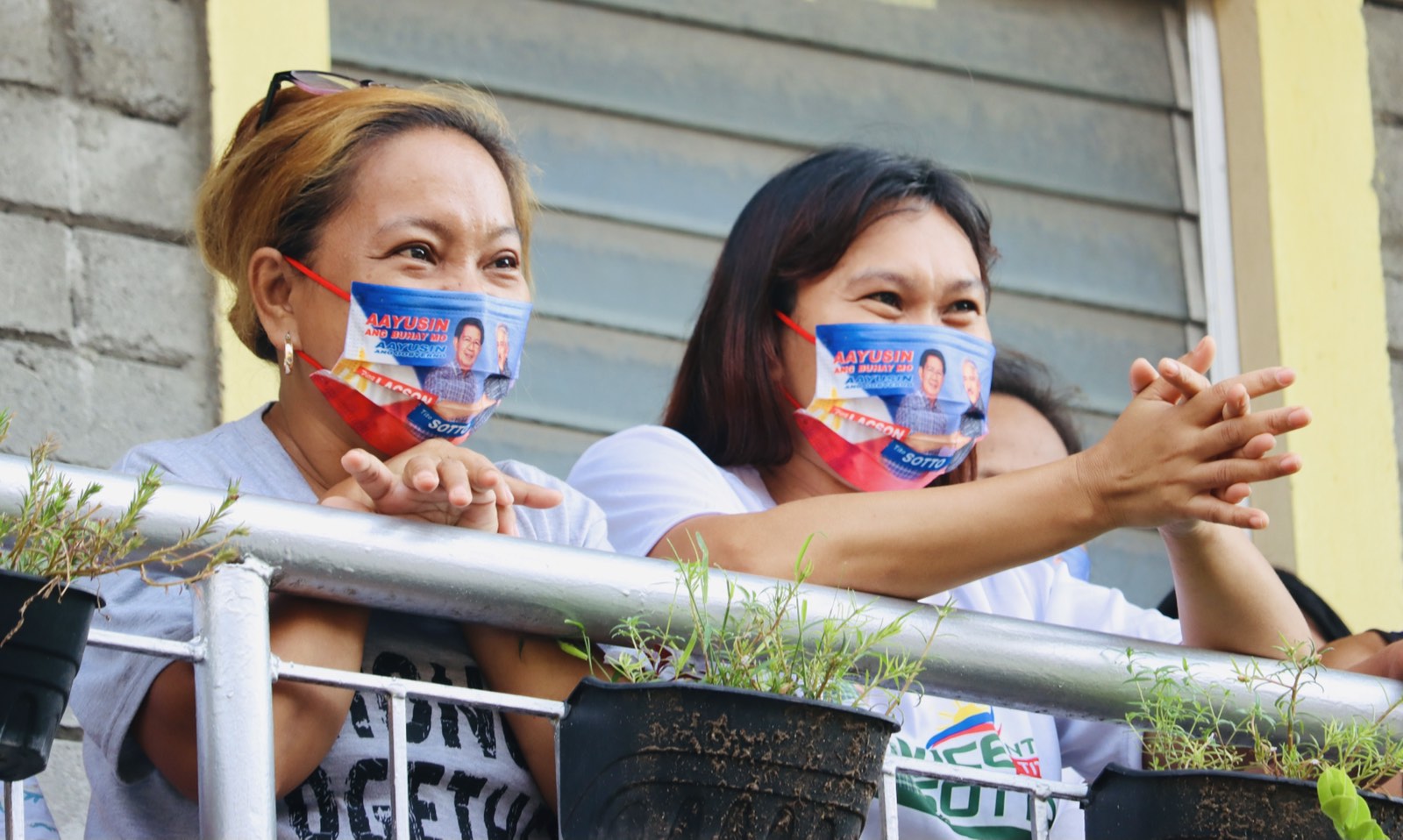 Two women stand on their apartment balcony to listen to Sotto, Lacson, and Eleazar during the March 26, town hall meeting at Brgy. 165. Photo by the Lacson-Sotto campaign team/Viber