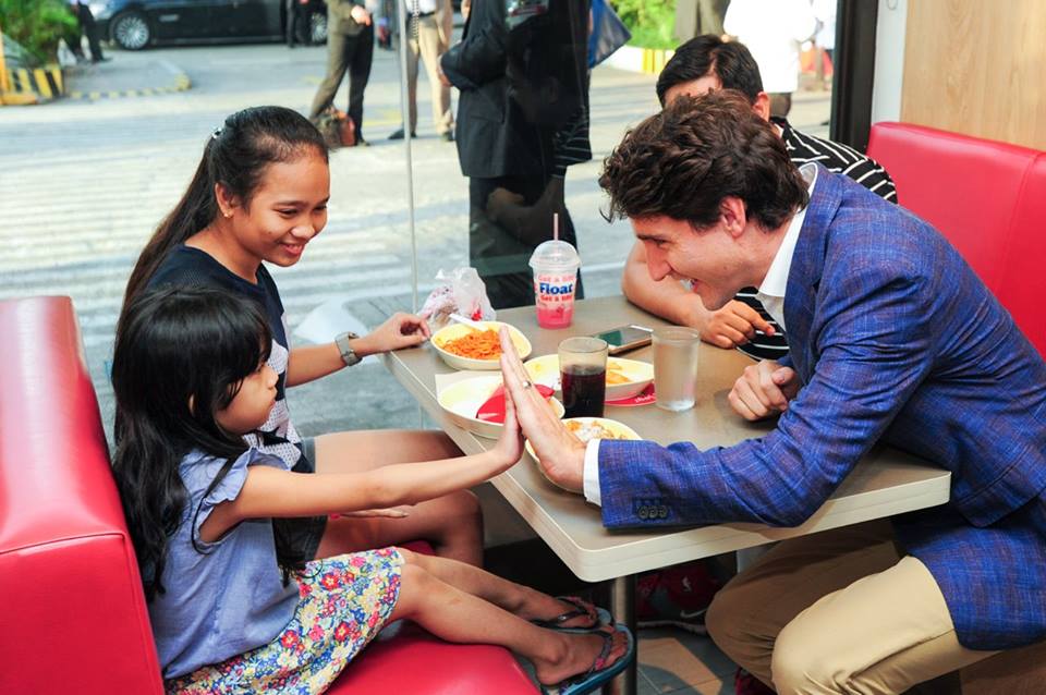 Canadian Prime Minister Justin Trudeau does a high five with a young girl at a Jollibee store in Tondo..jpg
